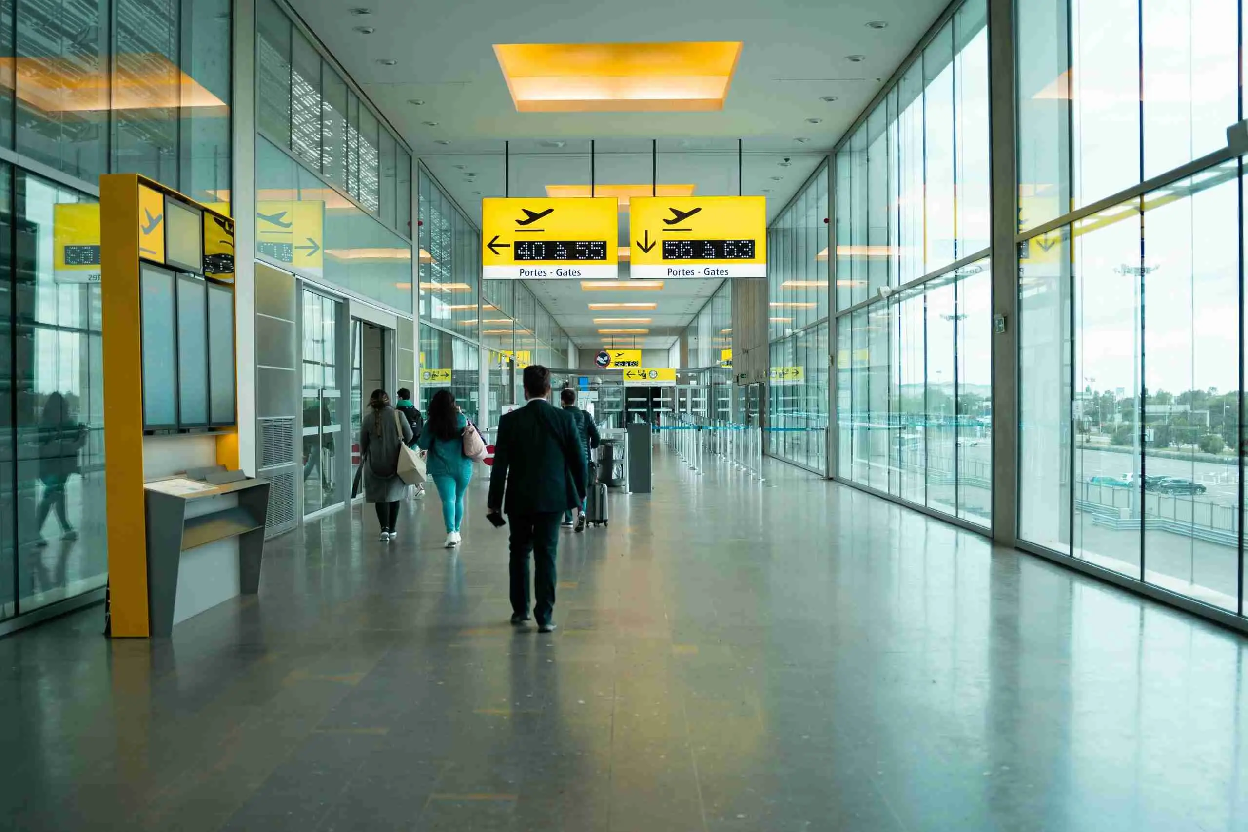 Passengers walking through a bright airport terminal towards the gates